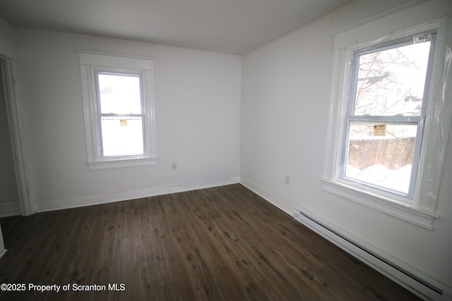 empty room with dark wood-type flooring and a baseboard heating unit