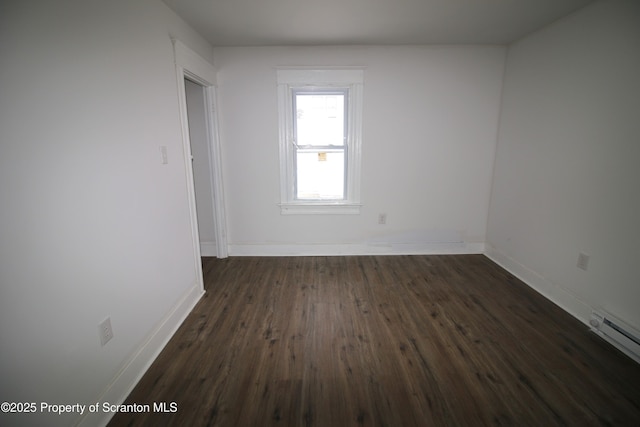 empty room featuring baseboard heating and dark hardwood / wood-style flooring