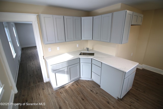 kitchen featuring dark wood-type flooring, gray cabinetry, and sink