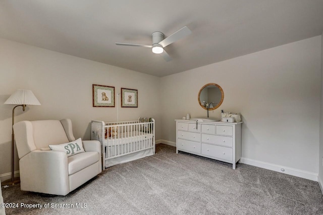 carpeted bedroom with ceiling fan and a nursery area