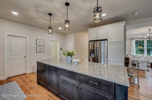 kitchen with stainless steel fridge, a kitchen island, and pendant lighting