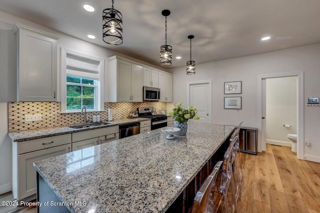 kitchen with pendant lighting, sink, a kitchen island, white cabinetry, and stainless steel appliances