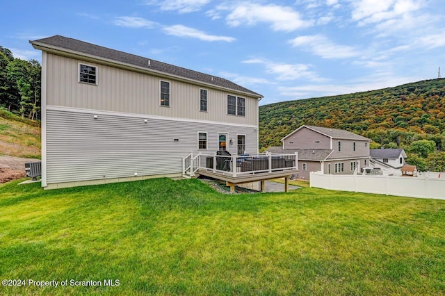 rear view of property with a lawn, cooling unit, and a wooden deck