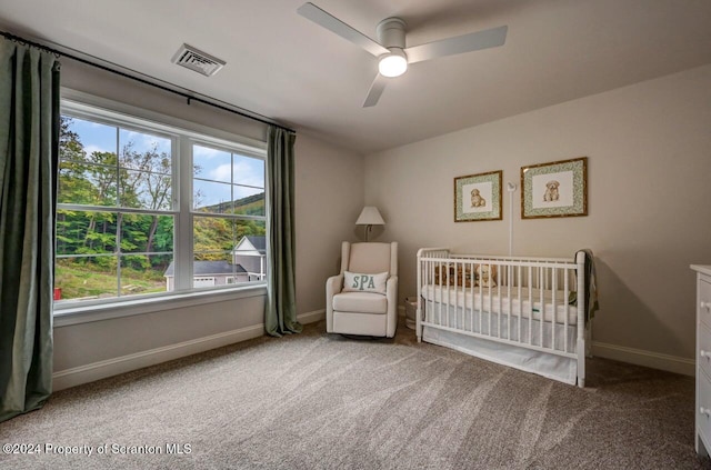 unfurnished bedroom with carpet flooring, a nursery area, and ceiling fan