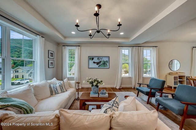 living room with light hardwood / wood-style floors, a raised ceiling, and a chandelier