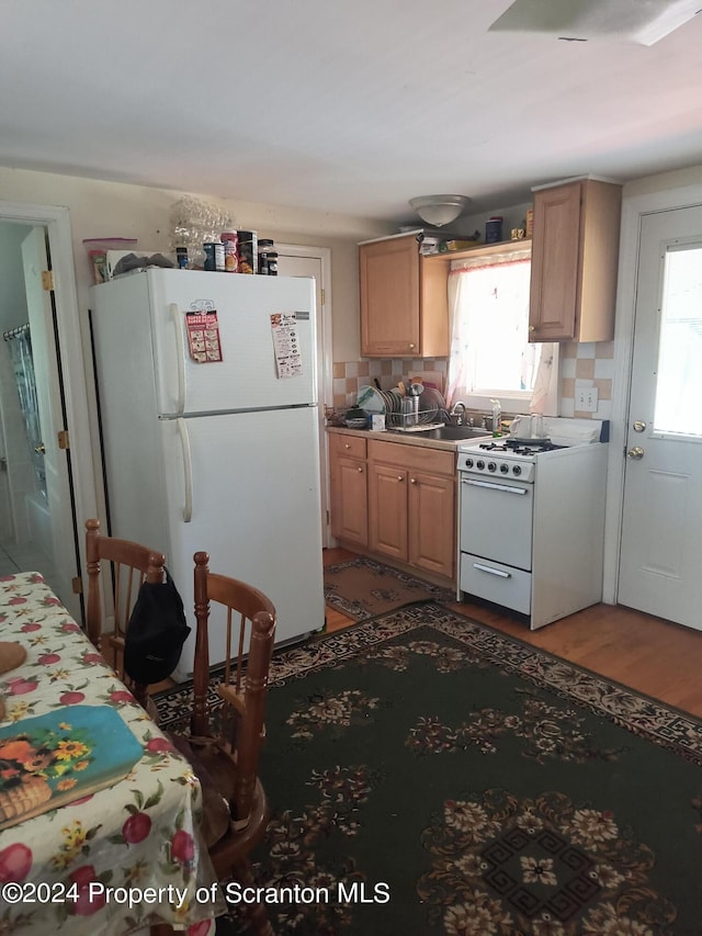 kitchen with light brown cabinets, white appliances, and hardwood / wood-style flooring