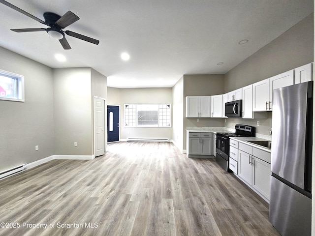 kitchen featuring stainless steel appliances, wood finished floors, light countertops, baseboard heating, and baseboards