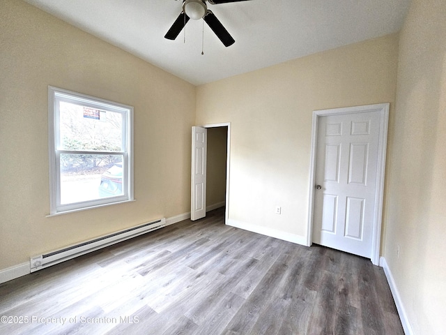 unfurnished bedroom with baseboards, a ceiling fan, baseboard heating, and wood finished floors