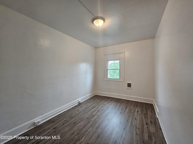 spare room with dark wood-style flooring, baseboards, and visible vents