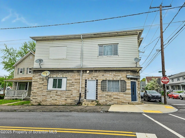 view of front facade featuring uncovered parking and stone siding