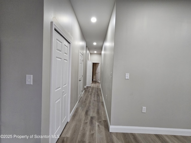 hallway featuring recessed lighting, baseboards, and wood finished floors