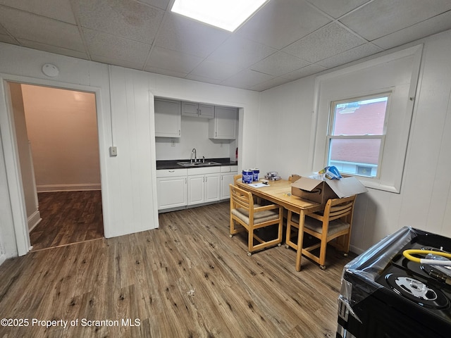 dining area featuring a paneled ceiling, baseboards, and wood finished floors