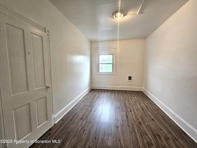 empty room with dark wood finished floors and baseboards