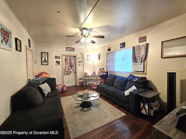 living room featuring cooling unit, ornamental molding, ceiling fan, dark wood-type flooring, and arched walkways