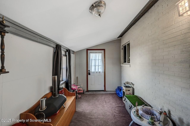 interior space featuring lofted ceiling and brick wall