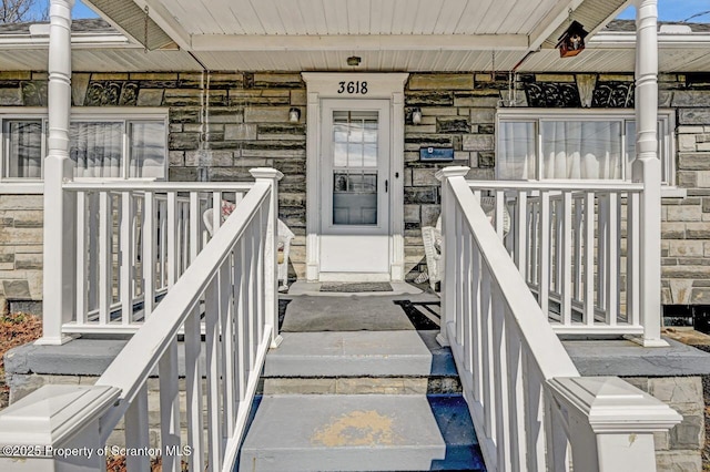 view of exterior entry featuring stone siding and a porch