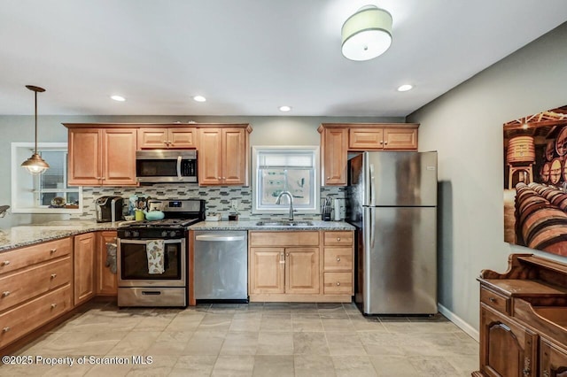 kitchen featuring backsplash, decorative light fixtures, light stone counters, stainless steel appliances, and a sink