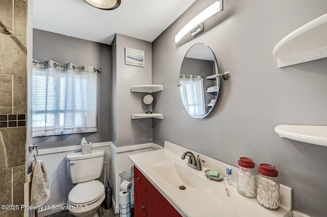 bathroom with a wainscoted wall, toilet, and vanity