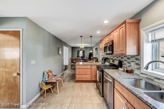 kitchen featuring light stone countertops, decorative backsplash, a peninsula, stainless steel appliances, and a sink