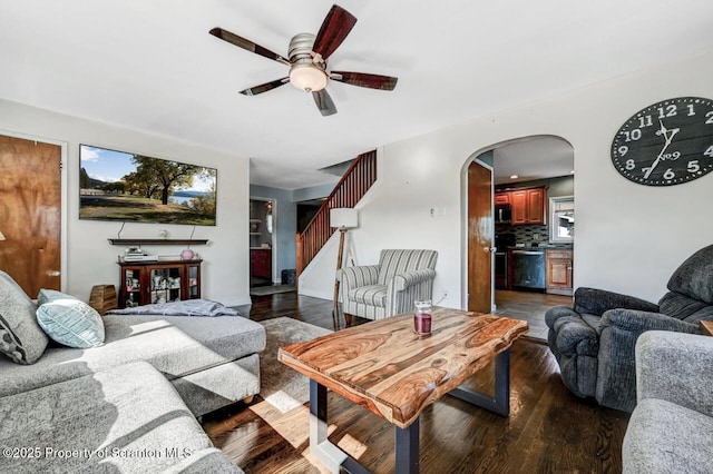 living room with arched walkways, stairs, a ceiling fan, and dark wood-style flooring