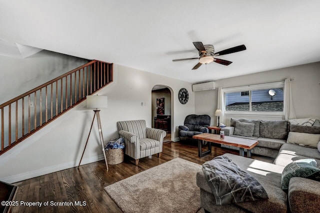 living area with stairs, a wall mounted AC, a ceiling fan, and wood finished floors