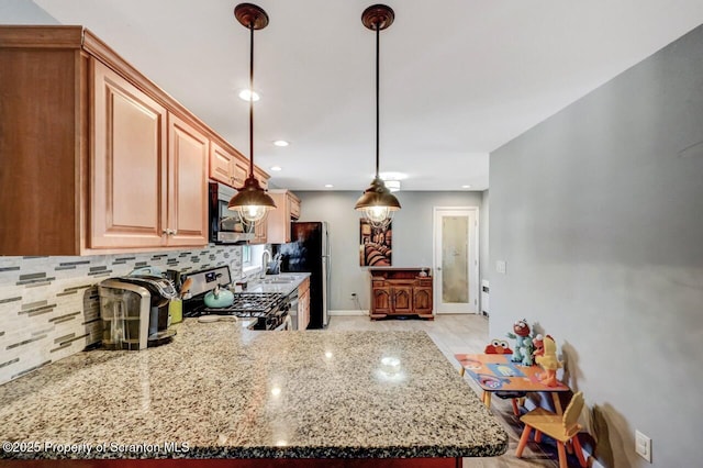 kitchen with decorative light fixtures, stainless steel appliances, light stone countertops, and tasteful backsplash