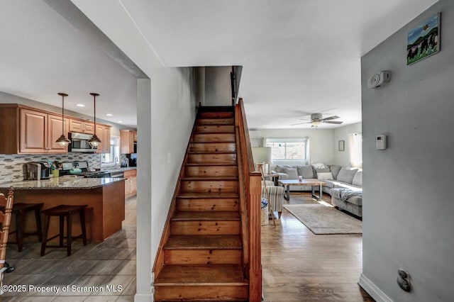 stairway with baseboards, ceiling fan, and wood finished floors