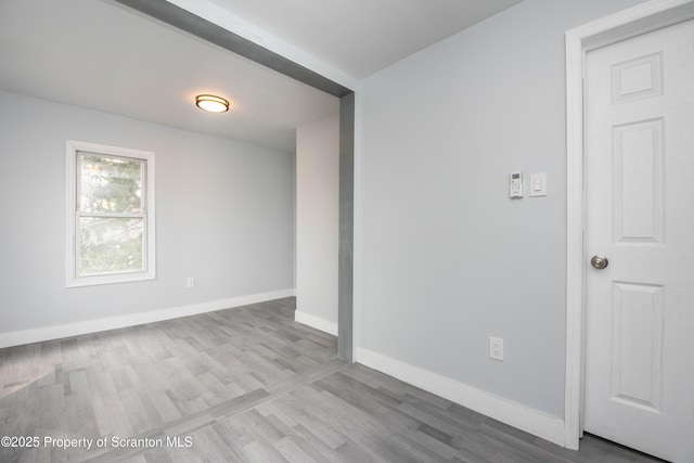 spare room featuring baseboards and wood finished floors