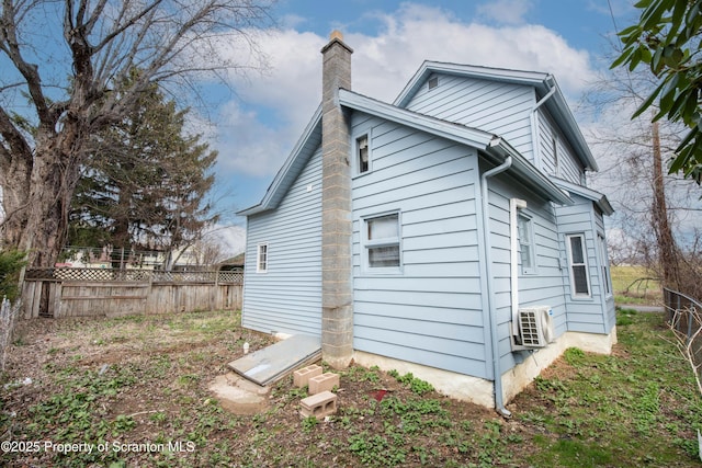 exterior space with a chimney, fence, and ac unit