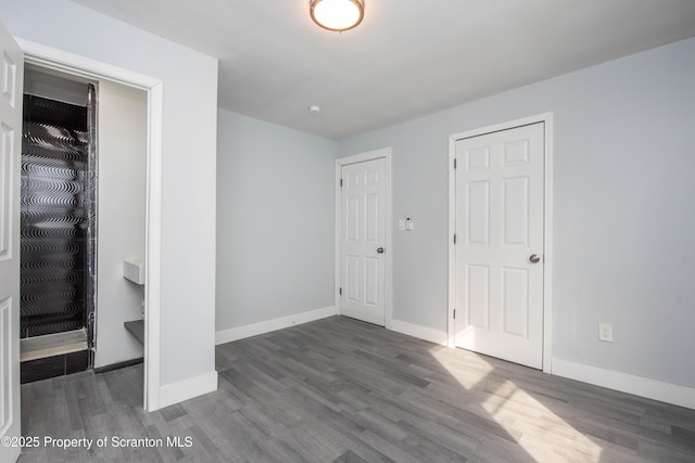 unfurnished bedroom with wood finished floors, a closet, and baseboards
