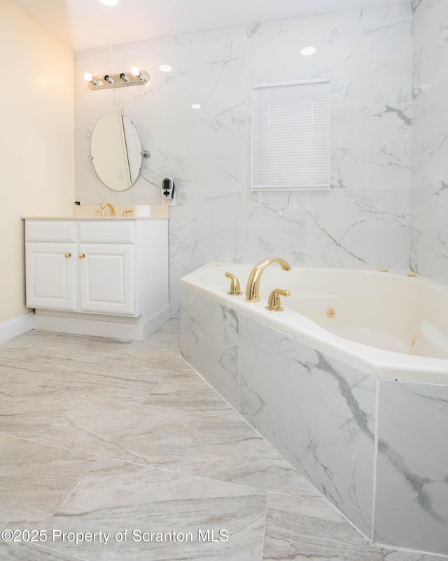 full bath with vanity, marble finish floor, and a tub with jets
