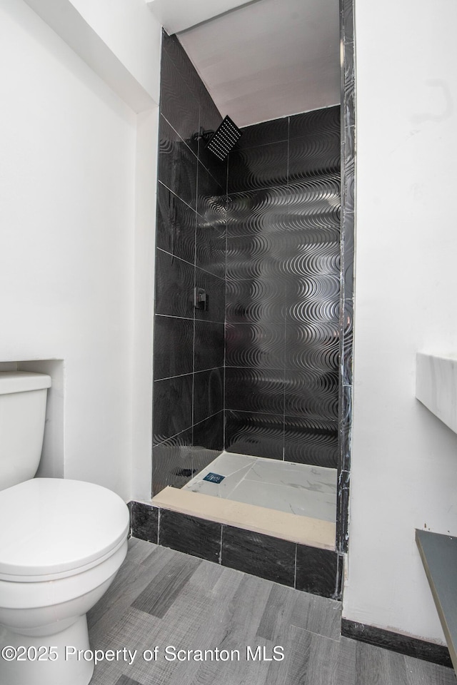 bathroom with tiled shower and toilet