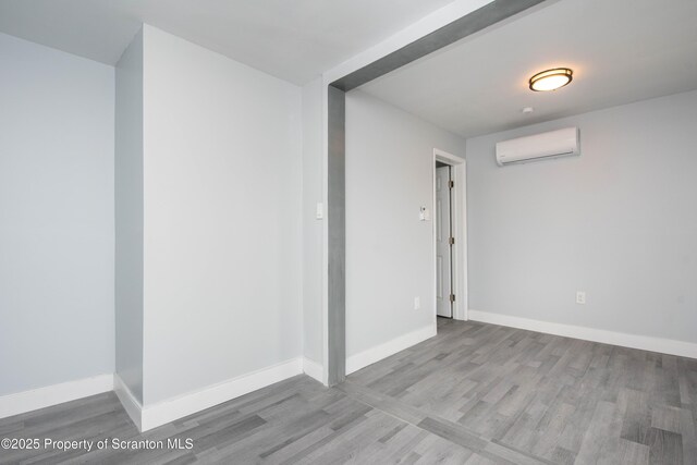 basement with baseboards, wood finished floors, and a wall unit AC