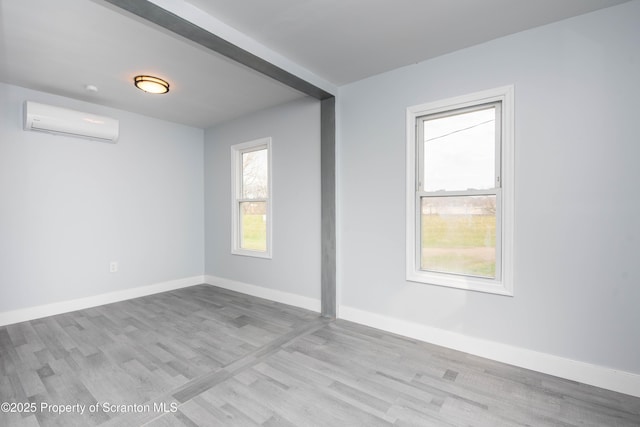 spare room with a wall mounted air conditioner, baseboards, and wood finished floors