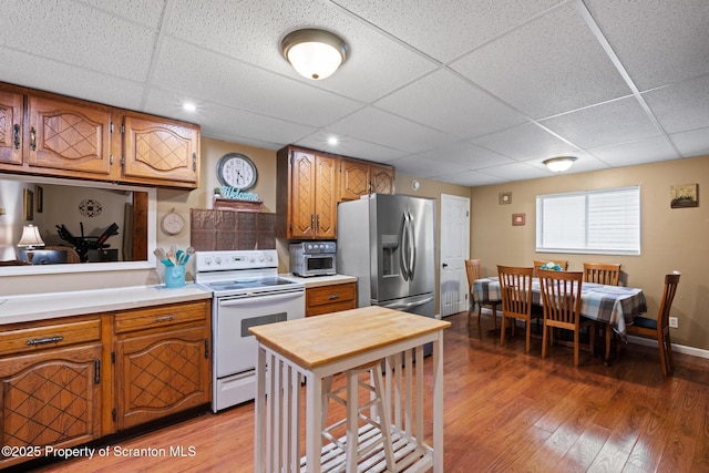 2211 Myrtle St, Scranton, PA 18510 - kitchen with white electric stove, a paneled ceiling, light wood finished floors, stainless steel fridge, and brown cabinets