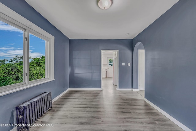826 Moltke Ave, Scranton, PA 18505 - spare room with radiator, arched walkways, healthy amount of natural light, and wood finished floors