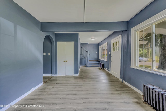 826 Moltke Ave, Scranton, PA 18505 - hallway featuring radiator heating unit, stairs, wood finished floors, and arched walkways