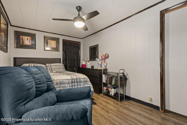 bedroom with ceiling fan, crown molding, and wood finished floors