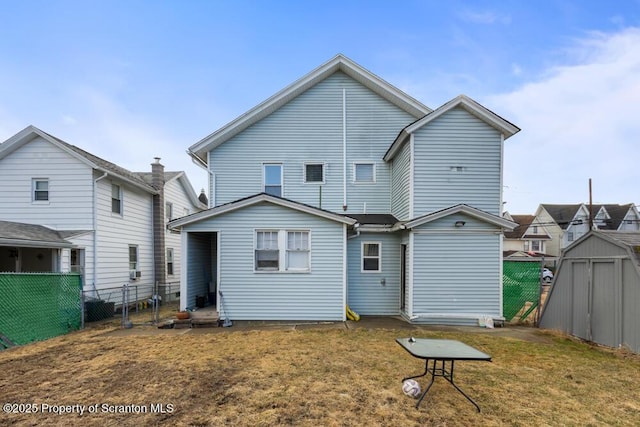 rear view of property featuring a storage shed, a yard, fence, and an outdoor structure