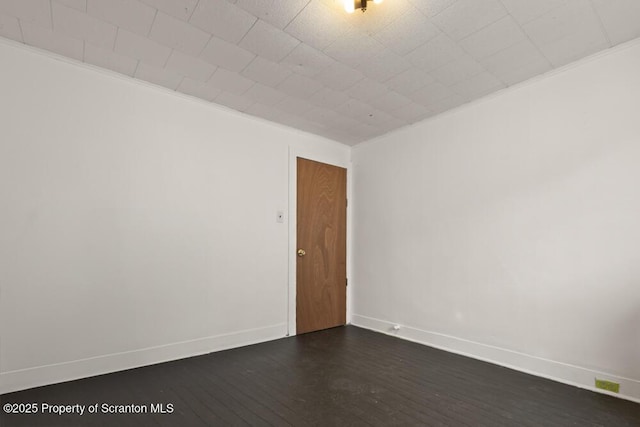 empty room with ornamental molding, dark wood-style flooring, and baseboards