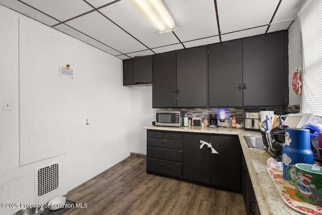 kitchen featuring visible vents, a drop ceiling, stainless steel microwave, dark wood-type flooring, and light countertops