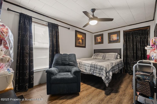 bedroom with a ceiling fan, ornamental molding, and wood finished floors