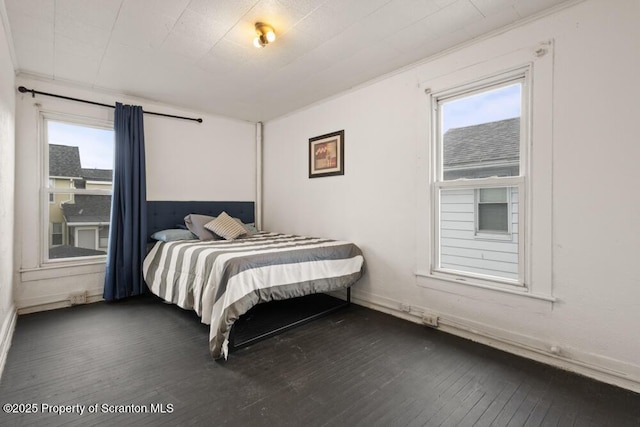 bedroom with dark wood-style flooring and multiple windows