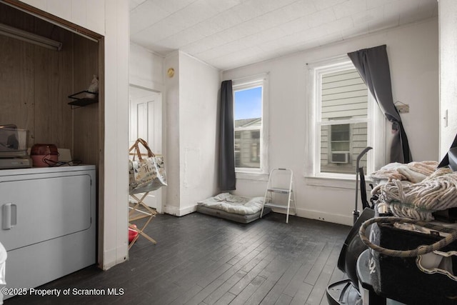 bedroom featuring baseboards, wooden walls, washer / clothes dryer, and dark wood-style flooring