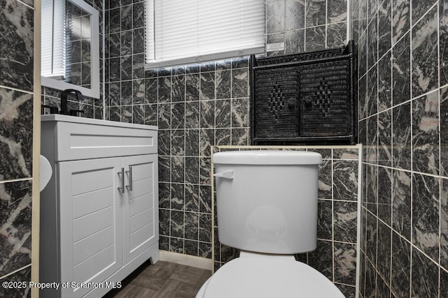 bathroom with toilet, tile walls, and vanity