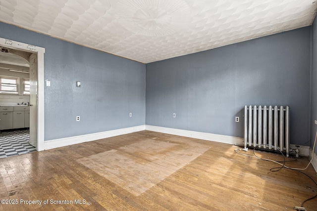 1132 Lloyd St, Scranton, PA 18508 - empty room with radiator, wood finished floors, and baseboards