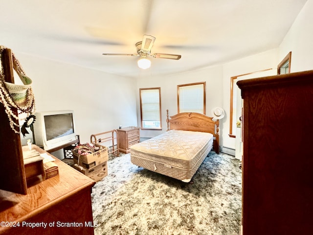 bedroom with ceiling fan, dark carpet, and a baseboard heating unit