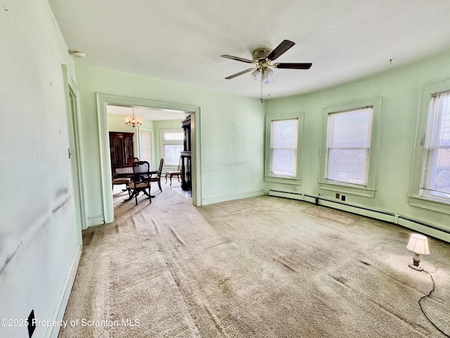 empty room with light carpet, a baseboard radiator, baseboards, and ceiling fan with notable chandelier