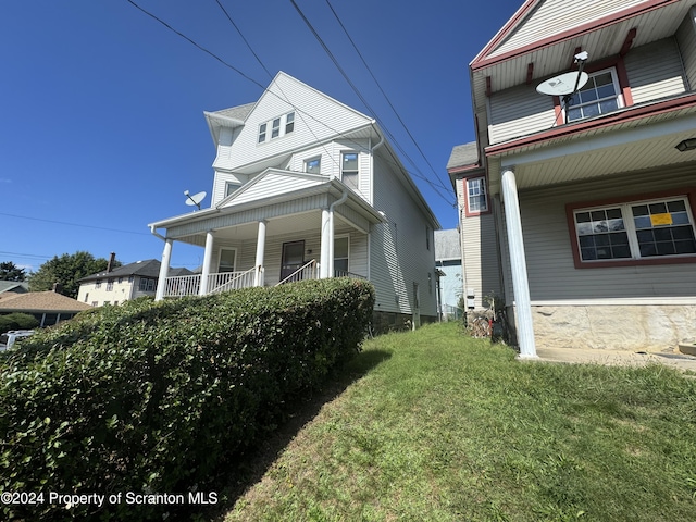 view of side of property featuring a lawn and covered porch