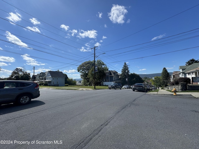 view of road with sidewalks, a residential view, curbs, and street lights